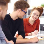 zwei junge M&auml;nner im B&uuml;ro und eine junge Frau im Hintergrund mit Blick nach vorn 