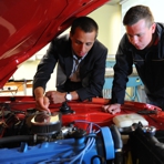 Auszubildende an der ge&ouml;ffneten Motorhaube eines Fahrzeuges