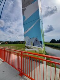 Br&uuml;ckenpfeiler mit Bild, auf dem ein Haus ist, im Hintergrund die Zwickauer Mulde