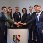 symbolischer Startknopf f&uuml;r den Breitbandausbau wird von sieben Vertretern des Projekts gedr&uuml;ckt